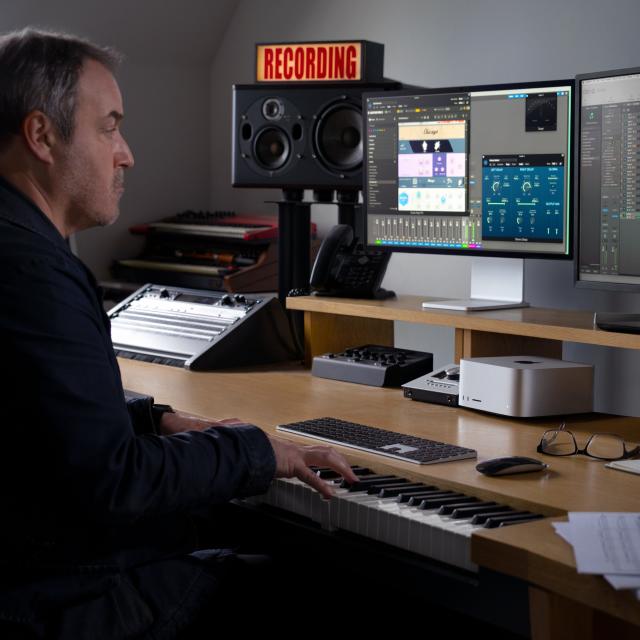 Person at desk using Mac Studio with multiple displays and playing a piano keyboard.