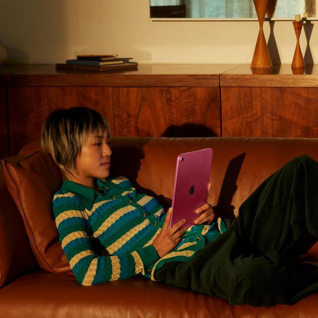 Person seated on a couch using iPad.