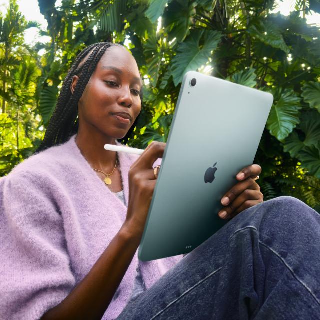 Person seated outdoors using iPad Air with Apple Pencil Pro.