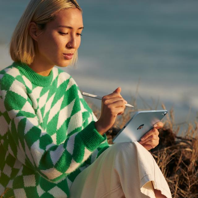 Person seated using iPad Mini and Apple Pencil outside
